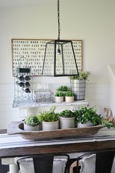 a dining room table with potted plants and wine glasses on the shelf above it