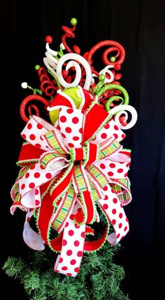 a red and white christmas bow on top of a green tree with polka dot ribbon