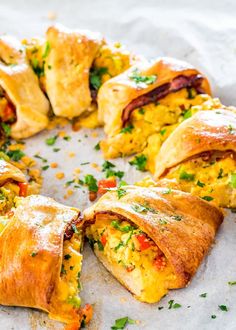 an egg and cheese breakfast roll is cut in half on a piece of parchment paper