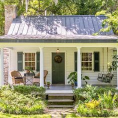 a white house with green shutters on the front porch and steps leading up to it