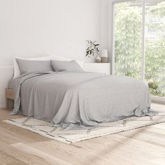 a bedroom with white walls and wooden floors, an area rug on the floor that has a bed in it