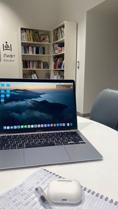 an open laptop computer sitting on top of a table next to a mouse and book