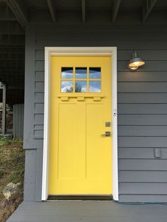 a yellow front door on a gray house