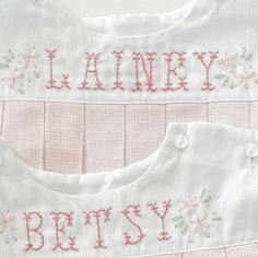 two white baby bibs with pink trims and flowers on the front, one is personalized