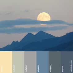 the full moon is setting over some mountains