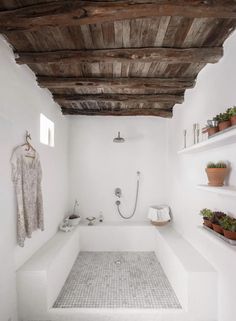 a white bathroom with wooden ceiling and shelves