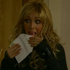 a woman holding a piece of paper with her mouth open and looking at the camera