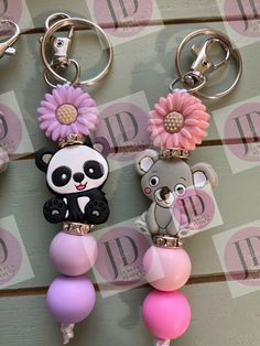 two key chains with panda bears and balloons attached to them, hanging on a wall