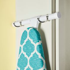 an ironing board hanging on the wall next to a blue and white towel rack