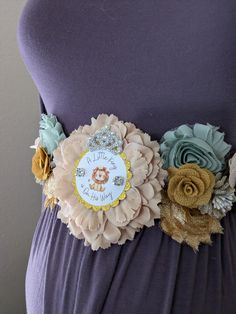 a woman wearing a purple dress with flowers on the waist and a lion brooch