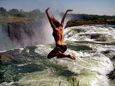 a person jumping into the water from a waterfall