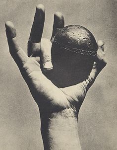 a person's hand holding an old ball in the air