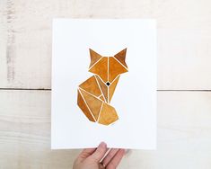 a person holding up a card with an origami fox on it