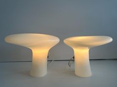 two white table lamps sitting next to each other on top of a gray flooring