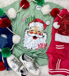 a green shirt with santa clause on it next to two pairs of sneakers and socks