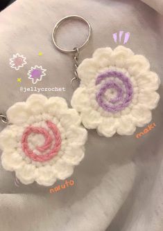 two crocheted flower keychains on top of a white blanket