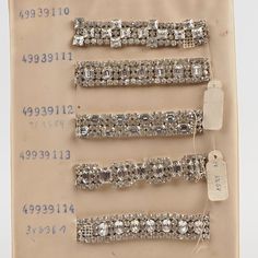 four pieces of silver colored hair clips with crystal stones on each side and a price tag attached to them