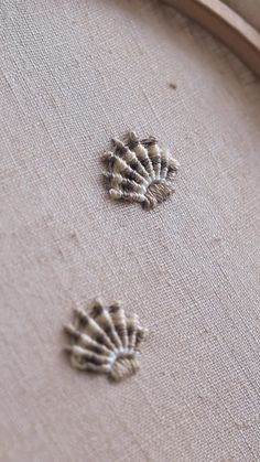 two embroidered shells sitting on top of a piece of fabric