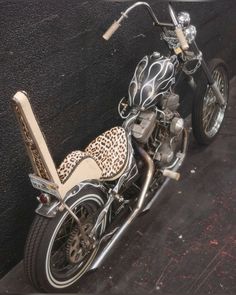 a motorcycle parked next to a wall on the side of a road with an animal print seat