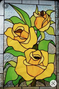 a stained glass window with three yellow roses