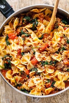 a pot filled with pasta and meat on top of a wooden table