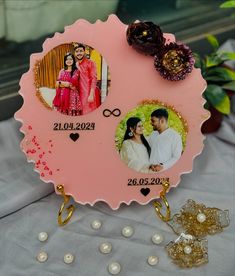 a couple's wedding photo on a pink plaque with pearls and flowers around it