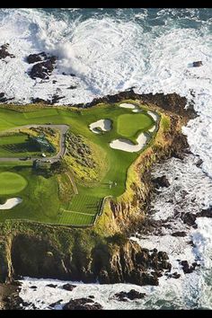 an aerial view of a golf course on the ocean with waves crashing in front of it