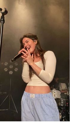 a woman singing into a microphone while standing in front of a microphone on a stage