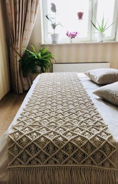 a bed with two pillows on top of it next to a potted plant and window