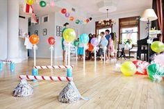 an indoor party with balloons, streamers and candy canes on the floor in front of people