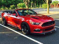 a red ford mustang convertible parked in a parking lot