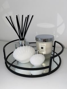 a candle and some candles sitting on a glass tray with black rimmings in front of a white wall