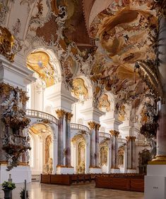 the interior of an ornate building with gold and white paint on the walls, ceiling and columns