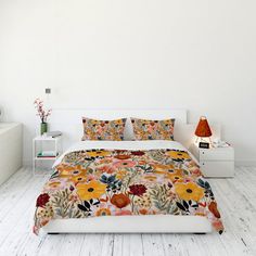 a bedroom with white walls and flooring has a floral comforter on the bed