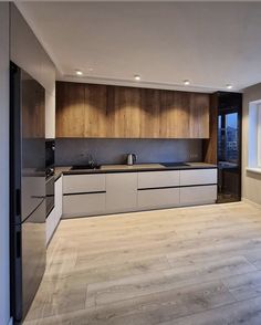 an empty kitchen with wooden cabinets and white counter tops, along with hardwood flooring