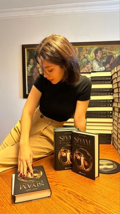 a woman sitting at a table with several books