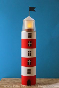 a small red and white lighthouse with a flag on it's top sitting on a wooden table