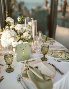 the table is set with white flowers and place settings