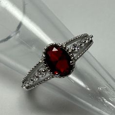 a close up of a ring with a red stone in it on a clear glass