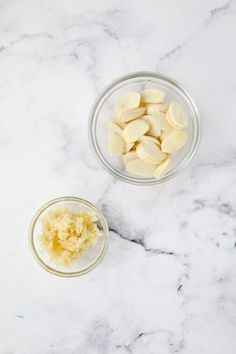 two bowls filled with peeled bananas on top of a white marble counter next to another bowl full of sliced bananas