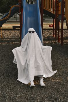 a white ghost is standing in front of a blue slide