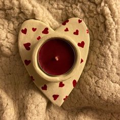 a heart shaped tea light holder with a candle in it on top of a blanket