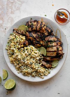 grilled chicken, corn and limes on a white plate with a glass of tea