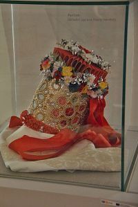 a glass case holding a red shoe with flowers on the top and an orange ribbon around it