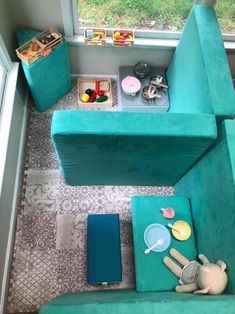 a small room with blue couches and toys on the floor in front of a window