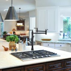 a kitchen with an island, stove and two pendant lights hanging over the counter top