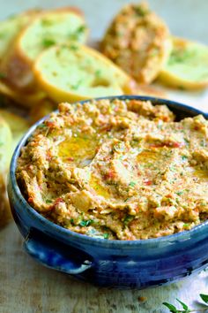 a blue bowl filled with hummus next to slices of bread