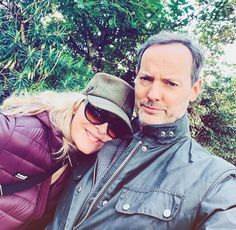 a man and woman taking a selfie in front of some trees with their arms around each other