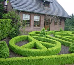 a house with a large garden in front of it and a green maze on the ground