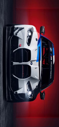 the front end of a white and blue sports car with its lights on, from above